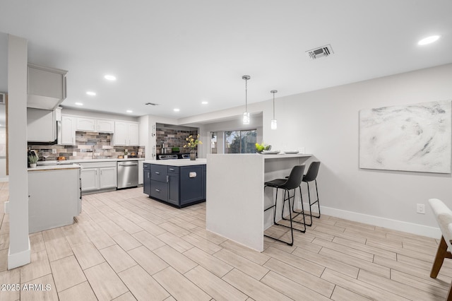 kitchen featuring a breakfast bar area, visible vents, light countertops, stainless steel dishwasher, and backsplash