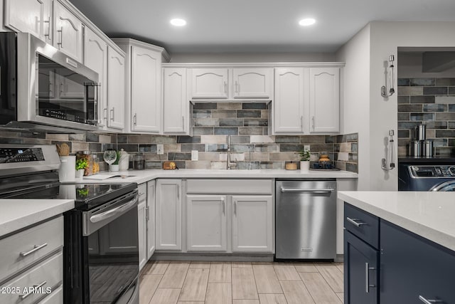 kitchen featuring appliances with stainless steel finishes, washer / clothes dryer, light countertops, and a sink