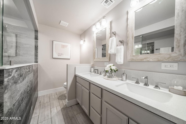 bathroom with visible vents, toilet, wood tiled floor, and a sink