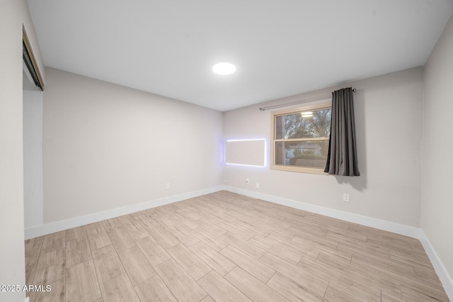 spare room featuring baseboards and wood finished floors