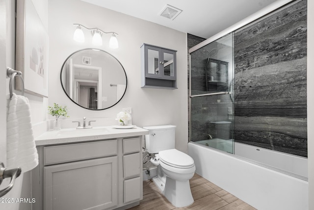 bathroom with visible vents, toilet, wood finished floors, combined bath / shower with glass door, and vanity