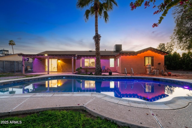 pool at dusk with a patio area, a fenced in pool, and cooling unit