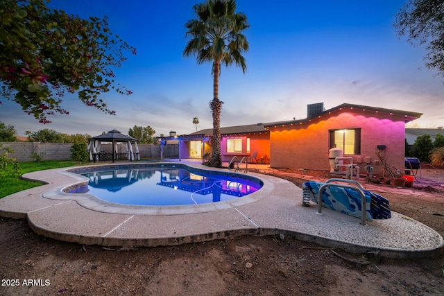 pool at dusk featuring a gazebo, a fenced in pool, a patio, and fence