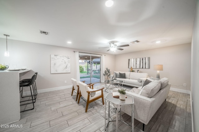 living room with wood finish floors, visible vents, baseboards, and ceiling fan