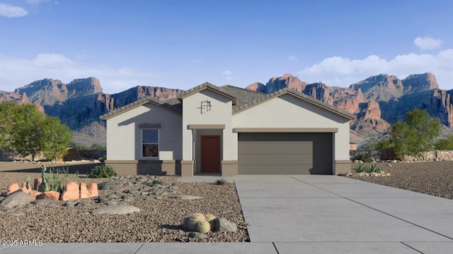 view of front of property featuring driveway, an attached garage, a mountain view, and stucco siding