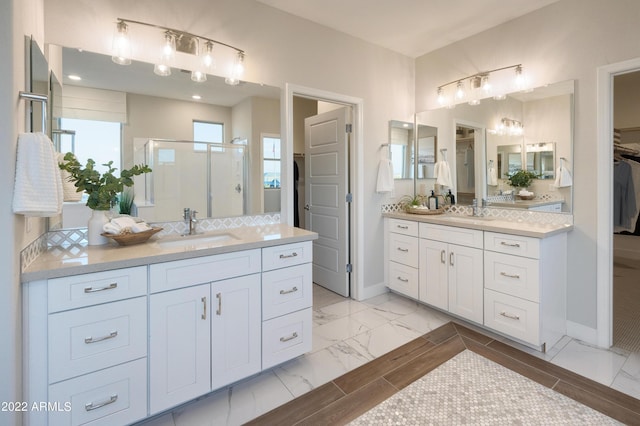 bathroom featuring a shower with door and vanity