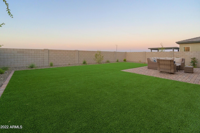 yard at dusk with an outdoor living space and a patio area