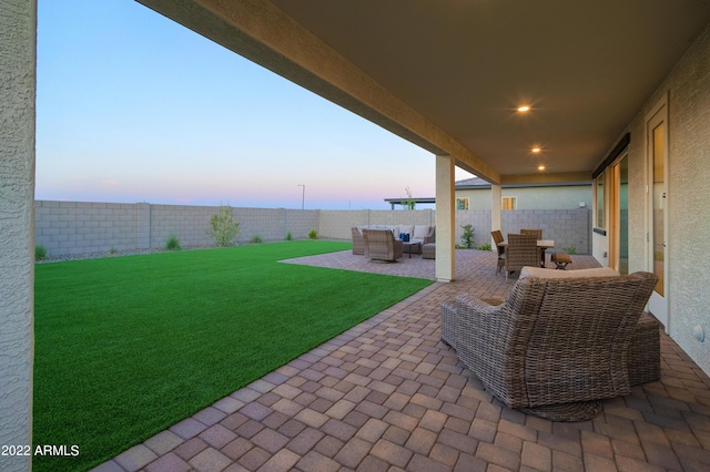 patio terrace at dusk with an outdoor living space and a lawn