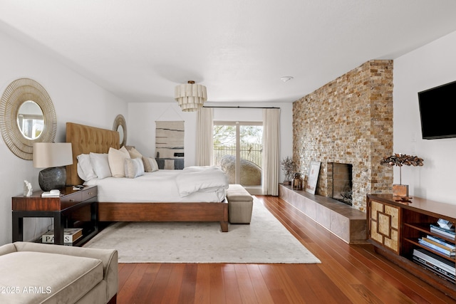 bedroom with hardwood / wood-style floors, access to outside, and a tile fireplace