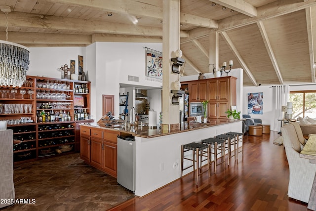 kitchen with stainless steel microwave, beam ceiling, a breakfast bar area, and wooden ceiling