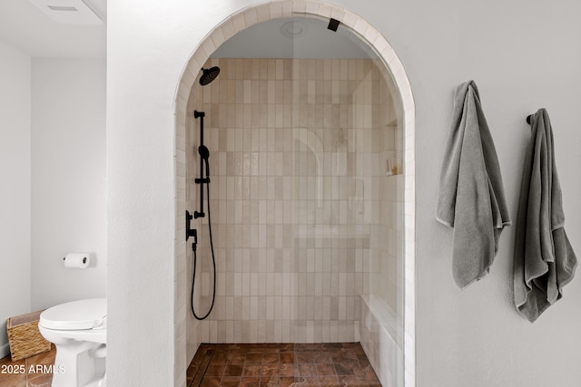 bathroom featuring toilet and tiled shower