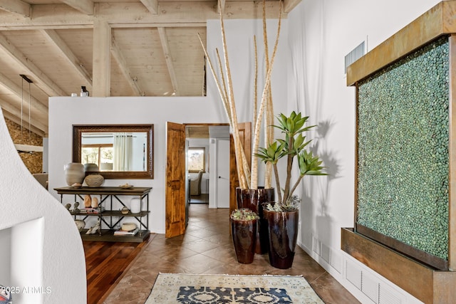 hallway with high vaulted ceiling, beam ceiling, tile patterned floors, and wooden ceiling