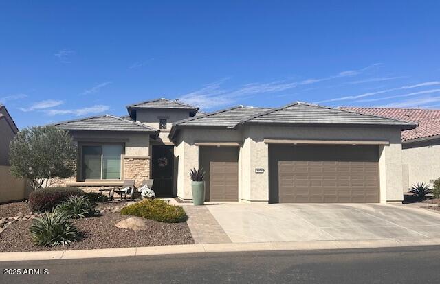 prairie-style home with a garage, driveway, and stucco siding