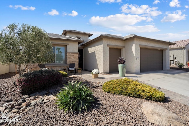 prairie-style home featuring stone siding, concrete driveway, an attached garage, and stucco siding