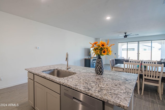 kitchen with ceiling fan, sink, light hardwood / wood-style flooring, stainless steel dishwasher, and a center island with sink