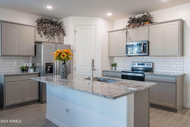 kitchen with backsplash, sink, light stone countertops, and stainless steel appliances