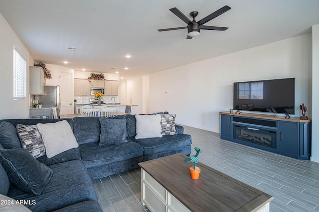 living room featuring ceiling fan, sink, and wood-type flooring