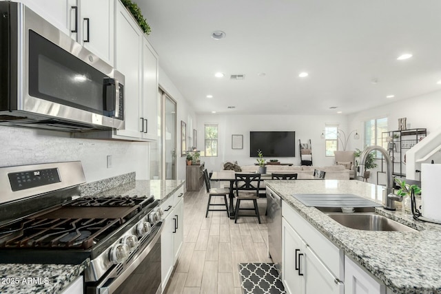 4110 S 58th Ln, Phoenix, AZ 85043 - kitchen featuring a sink, stainless steel appliances, open floor plan, and white cabinetry
