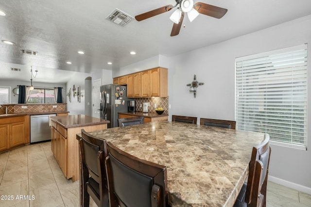 kitchen featuring backsplash, sink, stainless steel appliances, and a center island