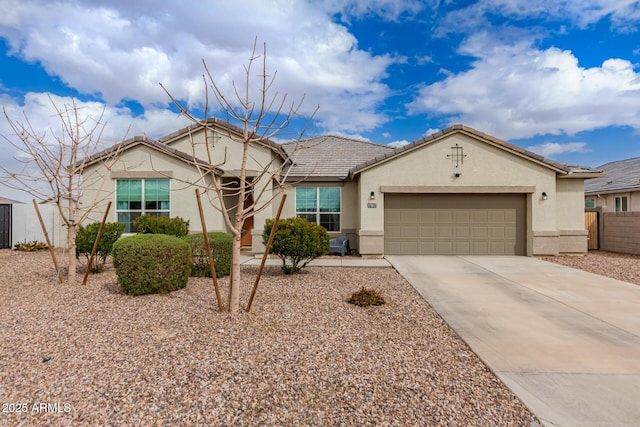 ranch-style house with fence, a tiled roof, concrete driveway, stucco siding, and an attached garage