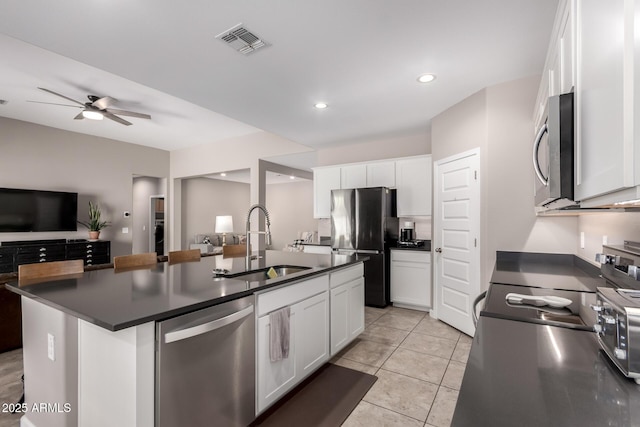 kitchen with dark countertops, visible vents, open floor plan, stainless steel appliances, and a sink