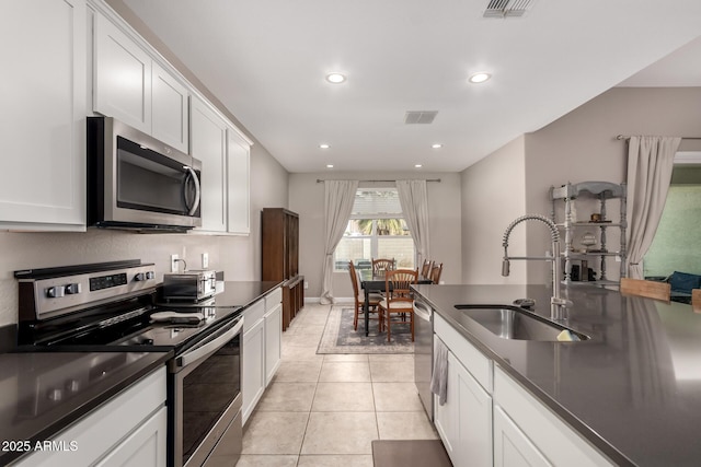 kitchen with a sink, stainless steel appliances, dark countertops, and visible vents