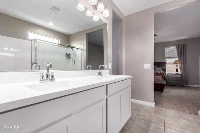 ensuite bathroom featuring tile patterned flooring, a shower stall, visible vents, and a sink