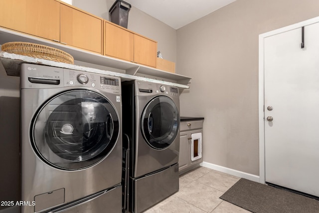 laundry room featuring washer and dryer, baseboards, cabinet space, and light tile patterned floors