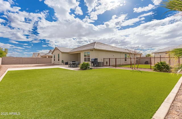 rear view of house with a patio area, stucco siding, a lawn, and a fenced backyard