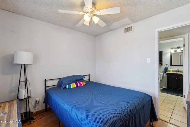 207 E Strahan Dr, Tempe, AZ 85283 - bedroom with a textured ceiling, a sink, wood finished floors, ceiling fan, and ensuite bathroom