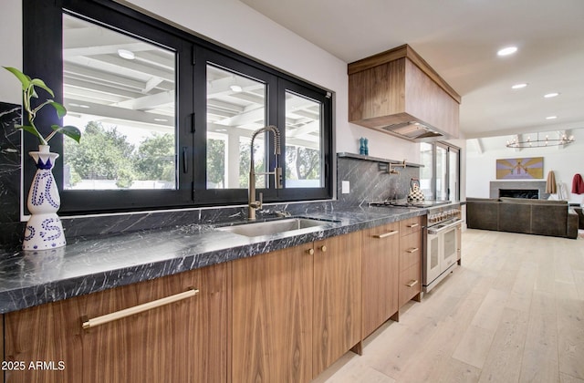 1712 E Fairfield St, Mesa, AZ 85203 - kitchen with range with two ovens, a fireplace, light wood-type flooring, modern cabinets, and custom exhaust hood