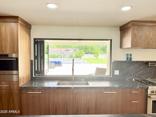 1712 E Fairfield St, Mesa, AZ 85203 - kitchen featuring stainless steel oven, modern cabinets, brown cabinets, tasteful backsplash, and dark stone countertops
