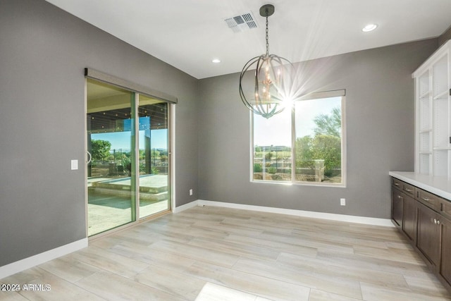 unfurnished dining area featuring a chandelier and light hardwood / wood-style flooring