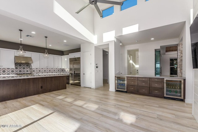 kitchen featuring dark brown cabinetry, beverage cooler, light hardwood / wood-style flooring, and stainless steel built in fridge