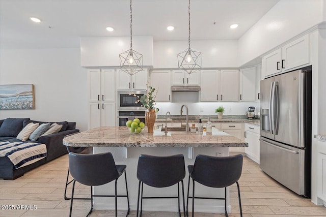 kitchen with white cabinetry, appliances with stainless steel finishes, sink, and a center island with sink