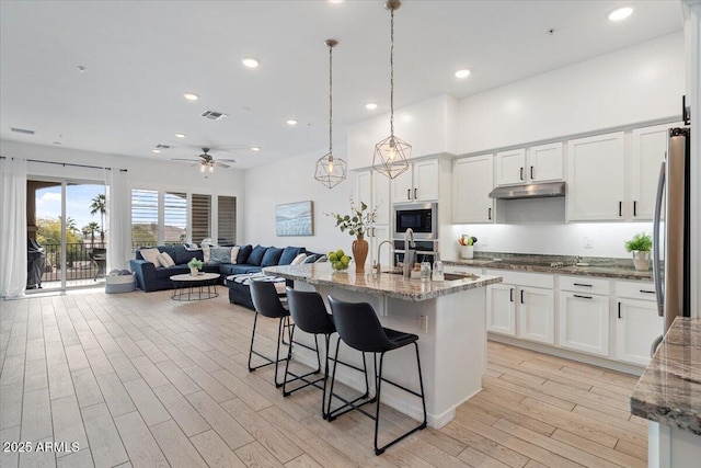 kitchen with decorative light fixtures, built in microwave, sink, stainless steel fridge, and white cabinets