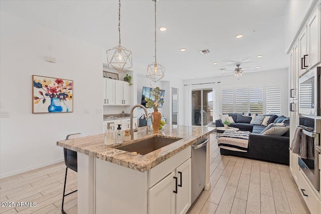 kitchen with white cabinetry, sink, and a kitchen island with sink