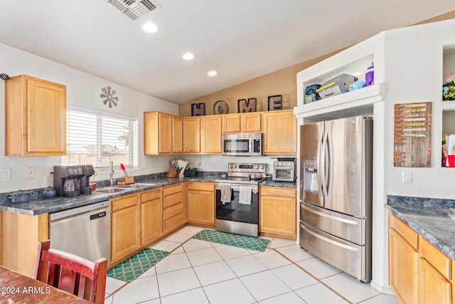 kitchen featuring light tile patterned floors, stainless steel appliances, lofted ceiling, and sink