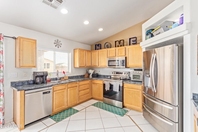 kitchen with sink, stainless steel appliances, vaulted ceiling, light brown cabinetry, and light tile patterned floors