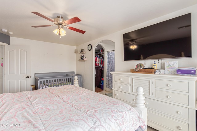 bedroom featuring a walk in closet, a closet, and ceiling fan