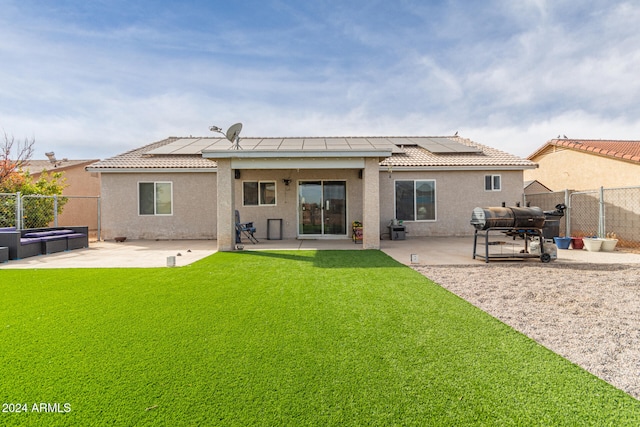 rear view of house with a patio area, a yard, and solar panels