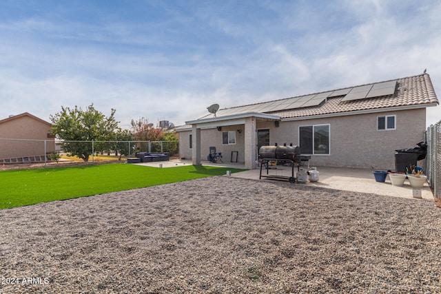 back of property featuring a lawn, solar panels, and a patio area