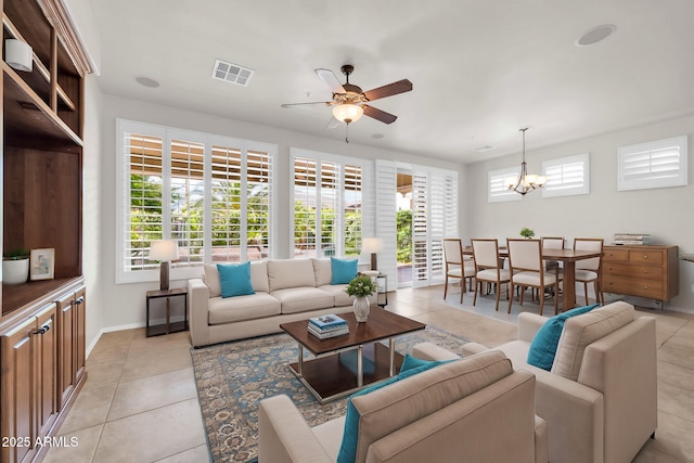 living area featuring light tile patterned floors, plenty of natural light, ceiling fan with notable chandelier, and visible vents