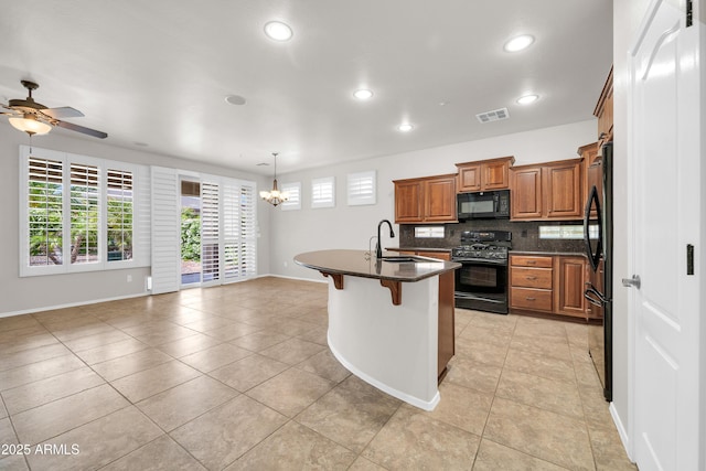 kitchen with decorative backsplash, visible vents, brown cabinets, a sink, and black appliances