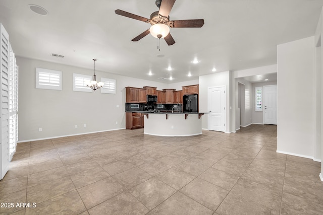 kitchen with a kitchen bar, visible vents, ceiling fan with notable chandelier, dark countertops, and black appliances