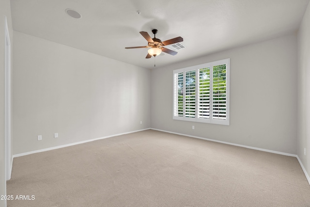 carpeted spare room with baseboards, ceiling fan, and visible vents