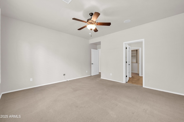 unfurnished bedroom with baseboards, a ceiling fan, a walk in closet, and carpet