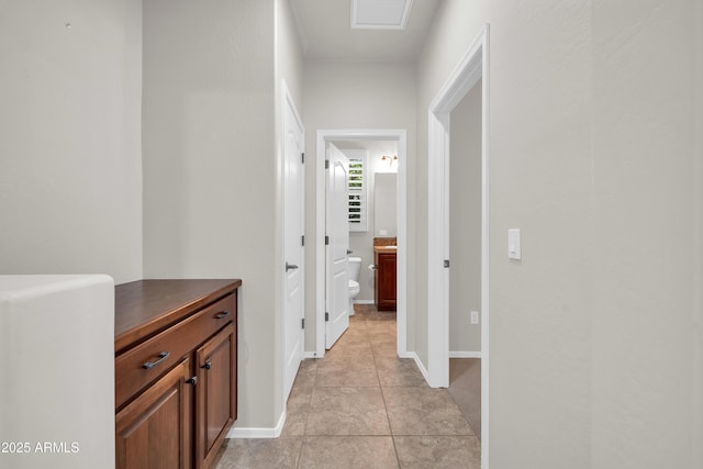 corridor featuring baseboards, visible vents, and light tile patterned floors