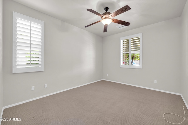 carpeted empty room featuring baseboards, visible vents, and a ceiling fan