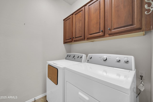 washroom featuring baseboards, cabinet space, and separate washer and dryer